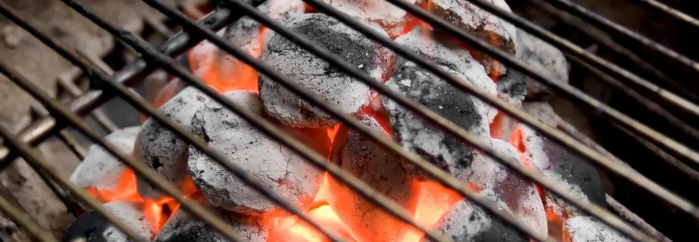 Heiß glühende Holzkohle unter einem Grillrost.